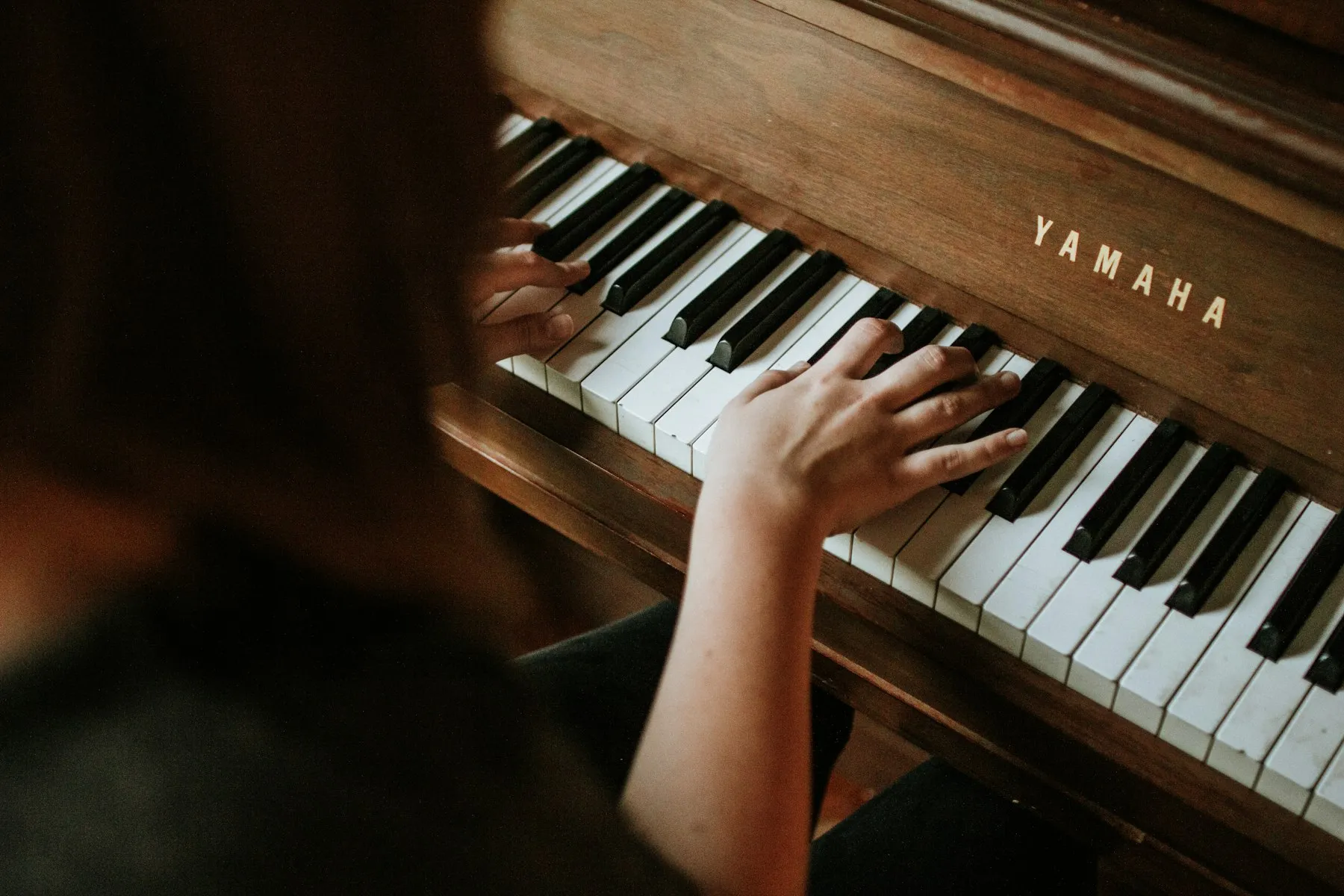 Hands playing an upright piano