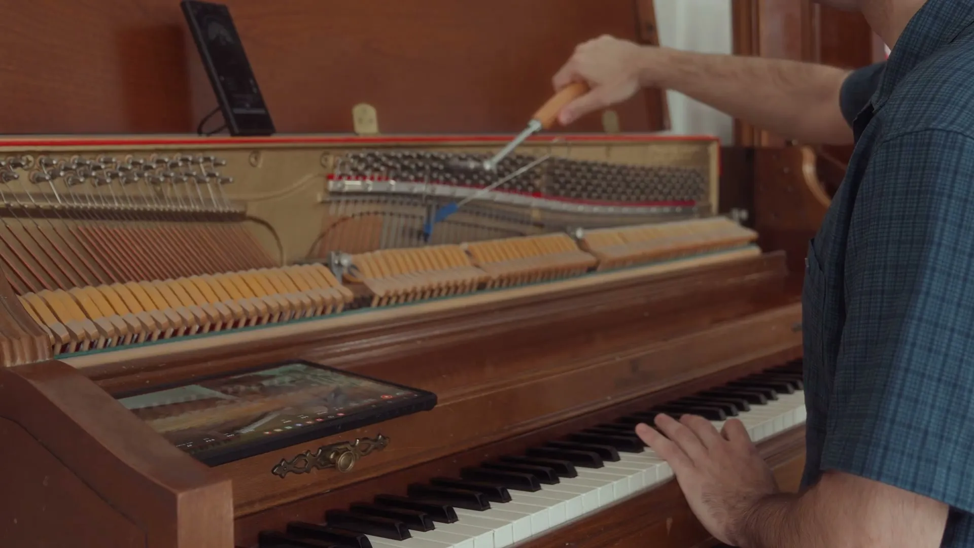 A TrueKeys technician tuning an upright piano in a family home
